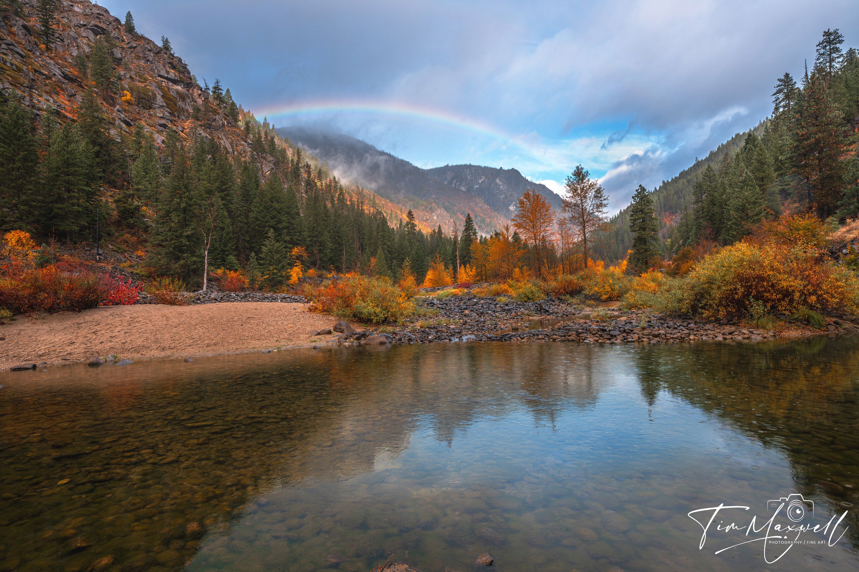 Rainbow over Tumwater Canyon with calm Wenatchee River and vibrant autumn foliage, fine art print by Tim Maxwell.