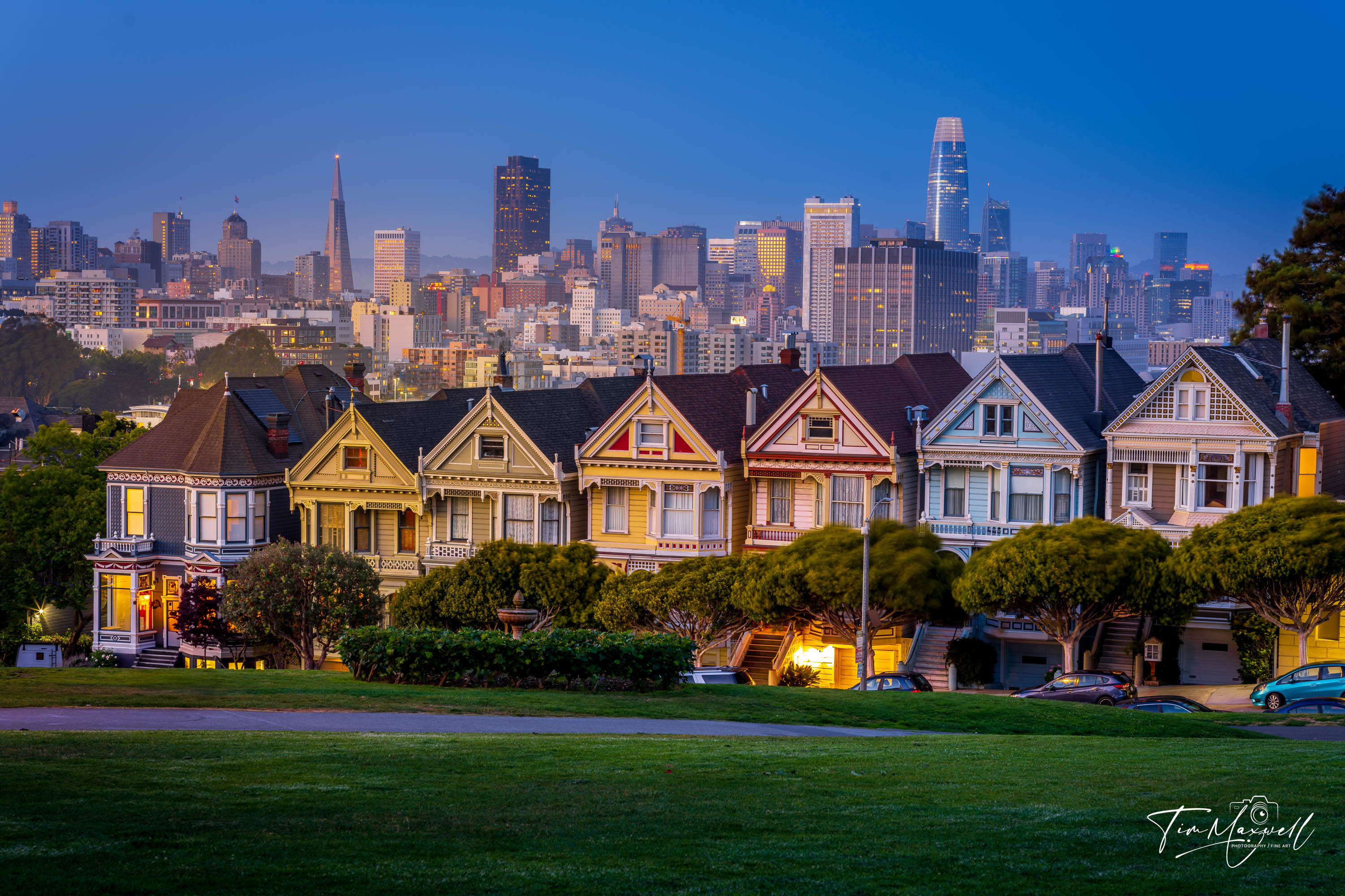 San Francisco’s Painted Ladies at blue hour with downtown skyline glowing in the background, viewed from Alamo Square