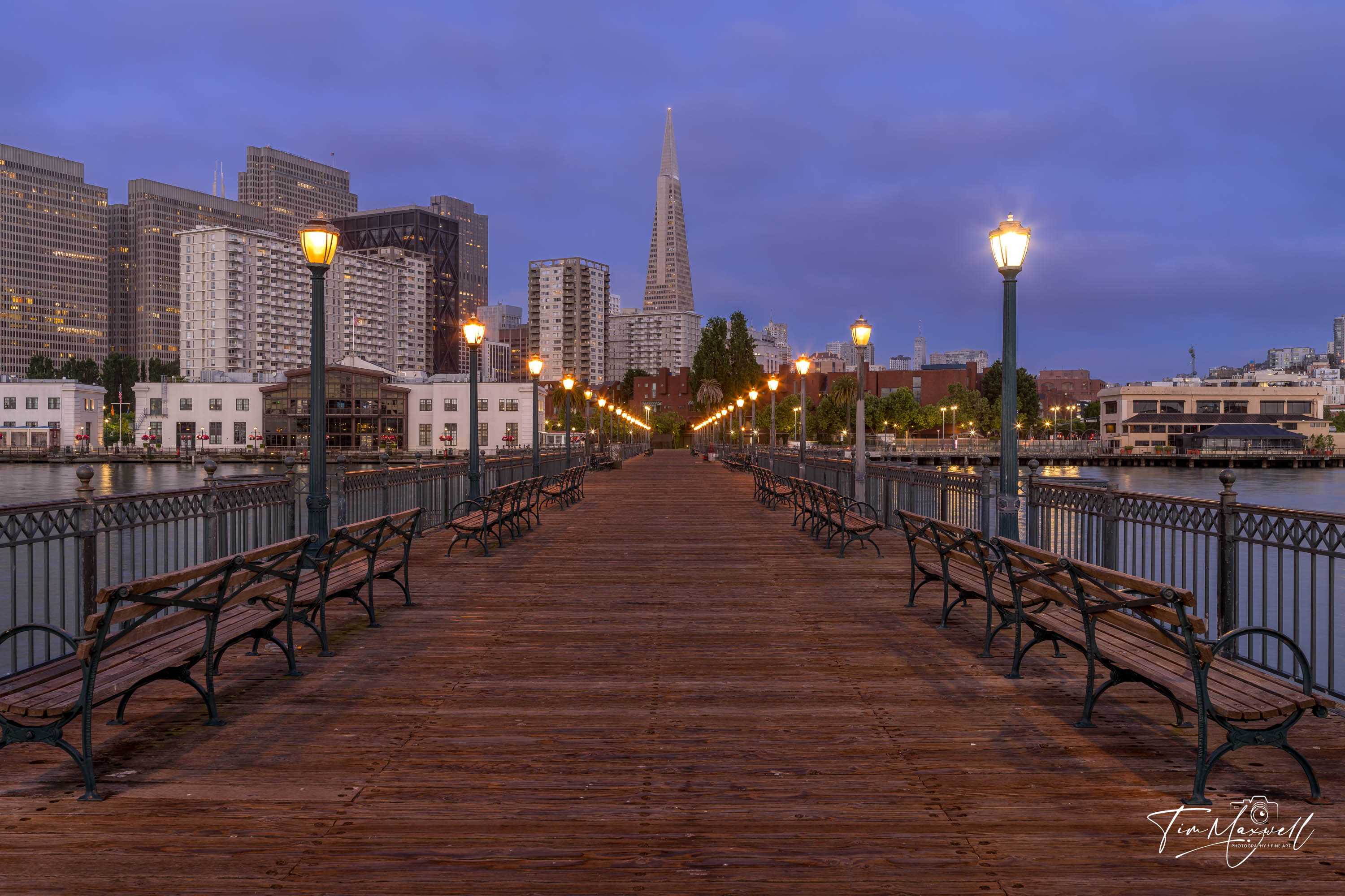 View from Pier 7 in San Francisco at sunrise with glowing street lamps and the Transamerica Pyramid in the distance
