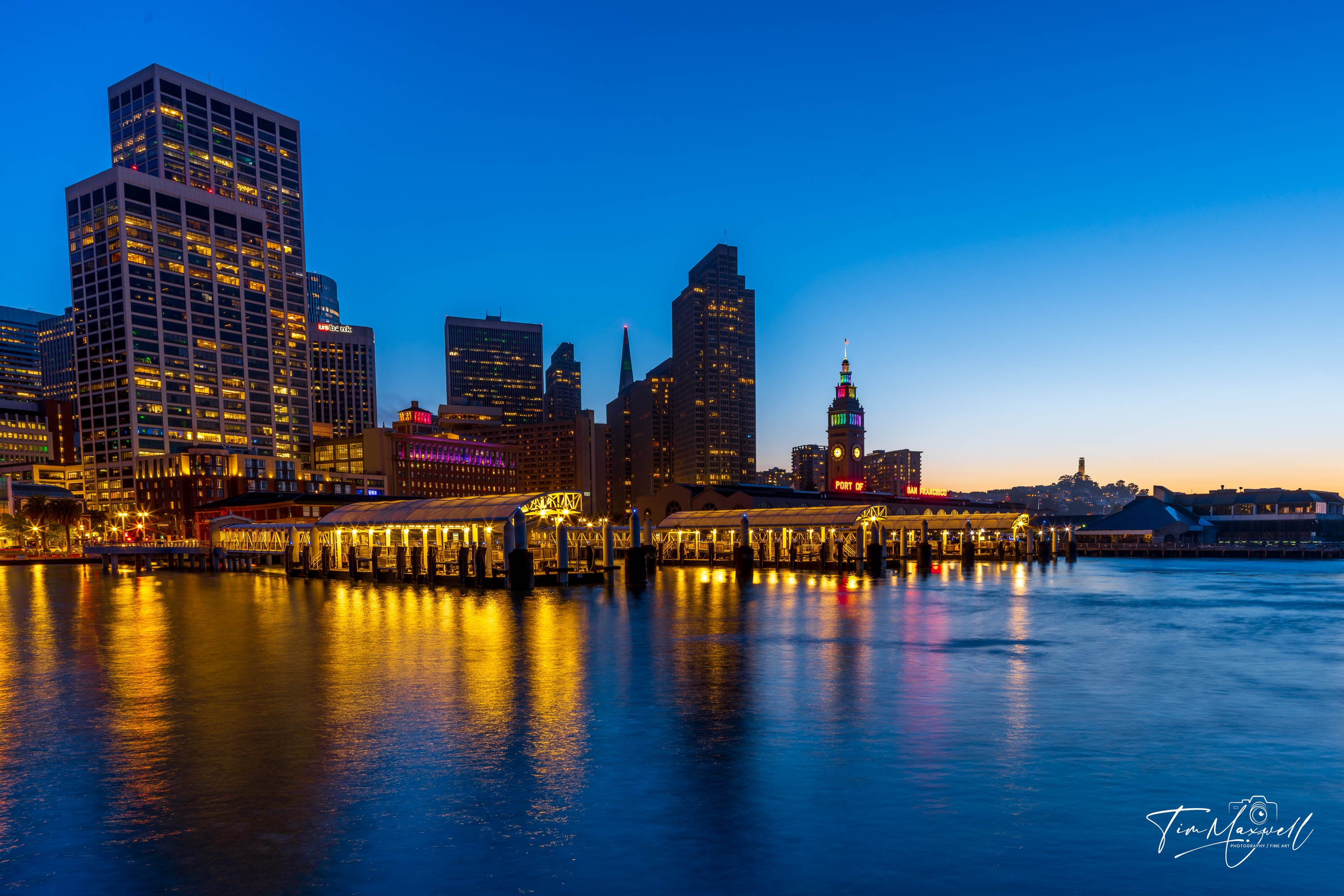 San Francisco Ferry Building at twilight with city lights reflecting on the bay, viewed from Pier 14