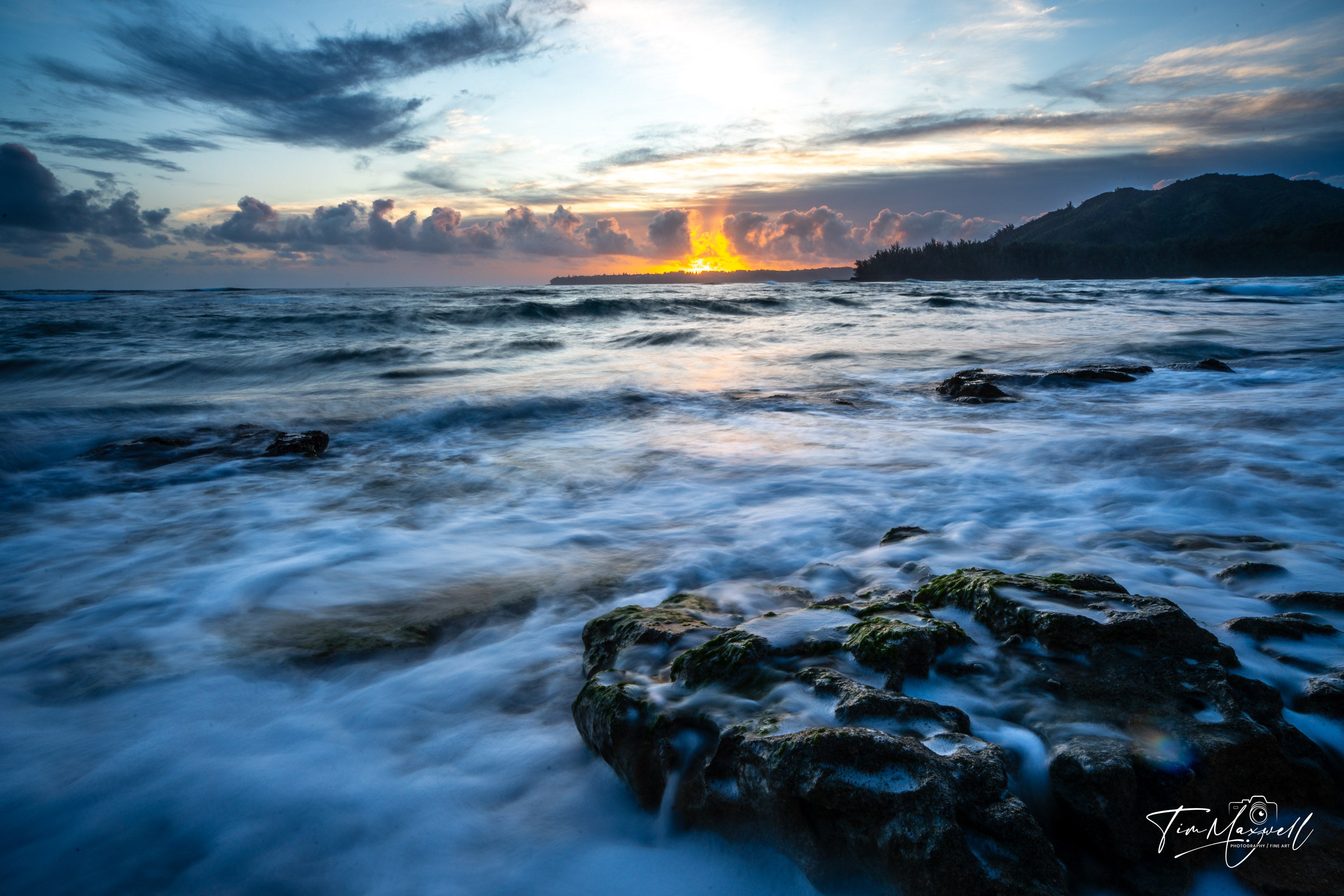Fiery sunset over rocky shoreline in Kauai, long-exposure fine art print by Tim Maxwell.