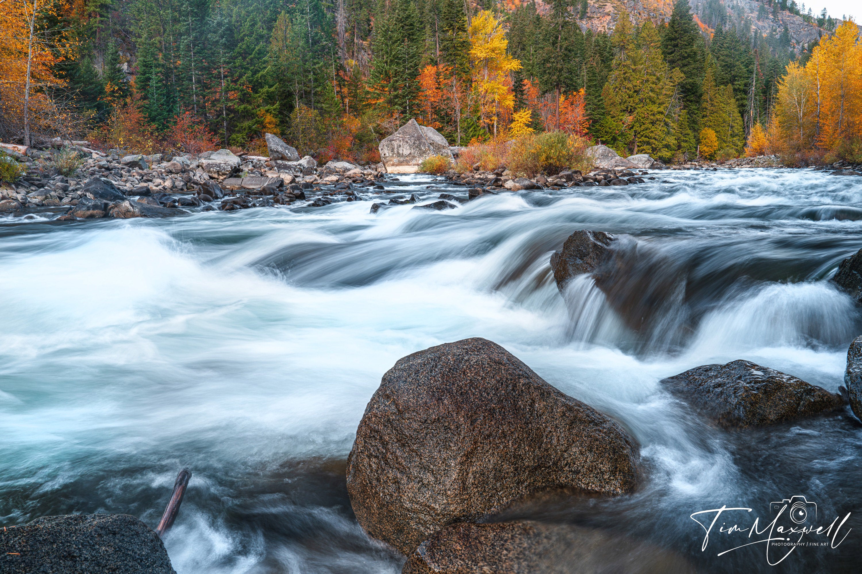 Long-exposure of the Wenatchee River in autumn near Leavenworth, water rushing over granite boulders; fine art print by Tim Maxwell.